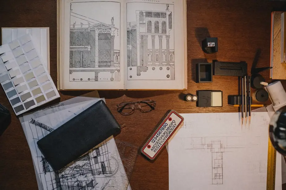 Vue d'ensemble d'un bureau d'architecture présentant différentes phases de conception : esquisses à main levée, plans architecturaux et vues 3D.